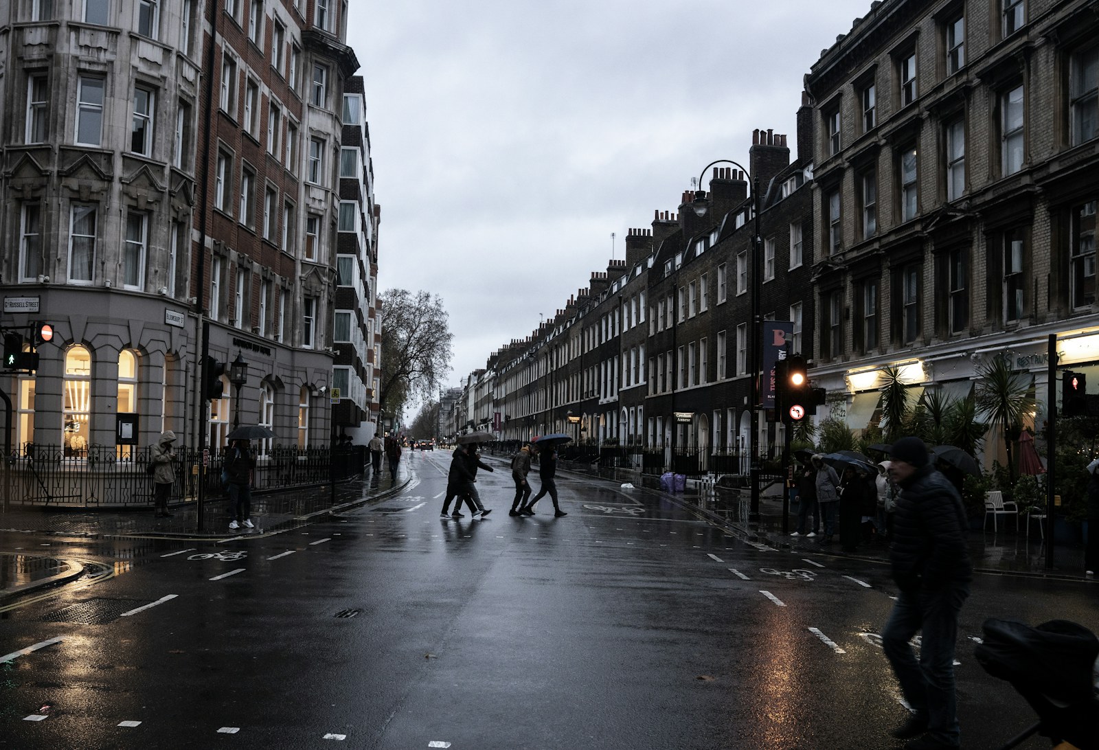 霧雨のロンドンの街角、人々が道を渡る様子